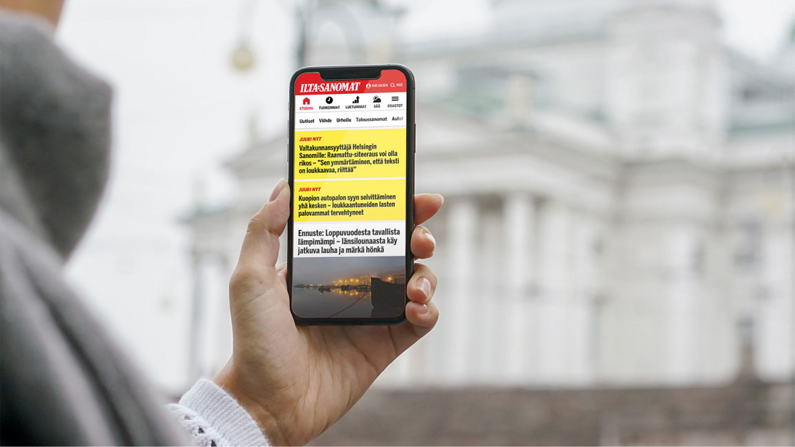 Hand holding a phone showing the Ilta-Sanomat new site.