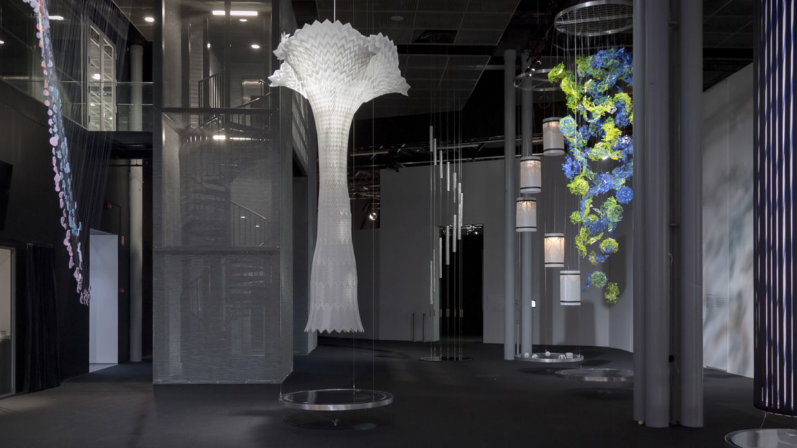 Exhibition space with several tall installations hanging from the ceiling