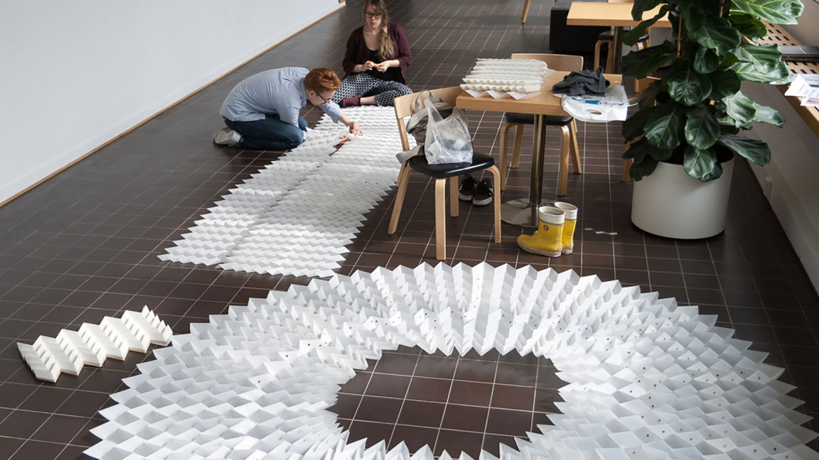 Two people sitting on the floor assempling folded sheets with magnets
