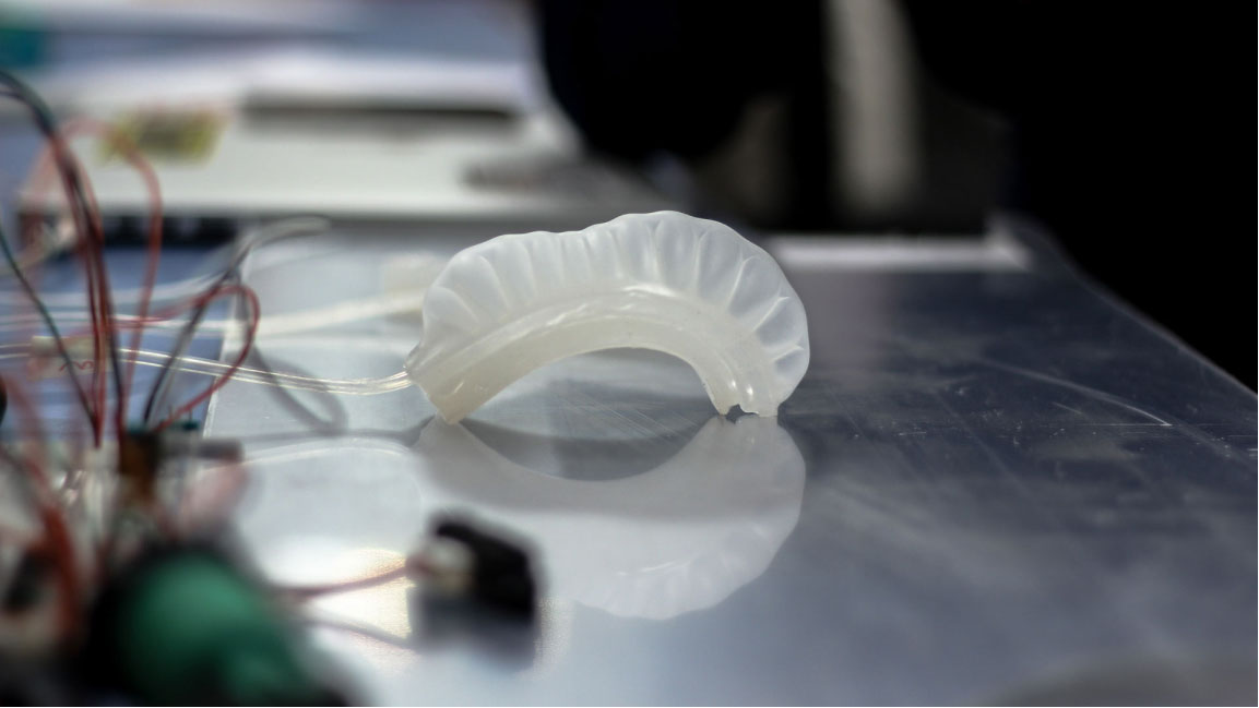 Silicone actuator in the shape of a bending tube standing on a table